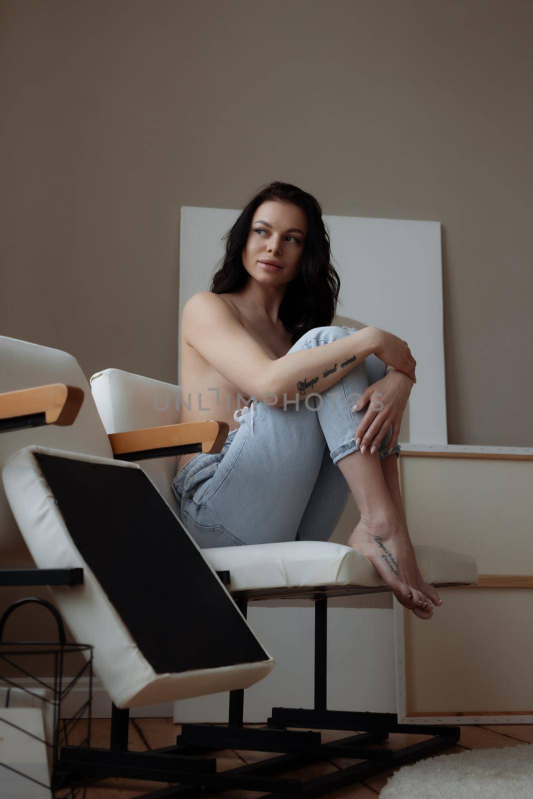 Relaxed topless woman sitting on chair at home by 3KStudio