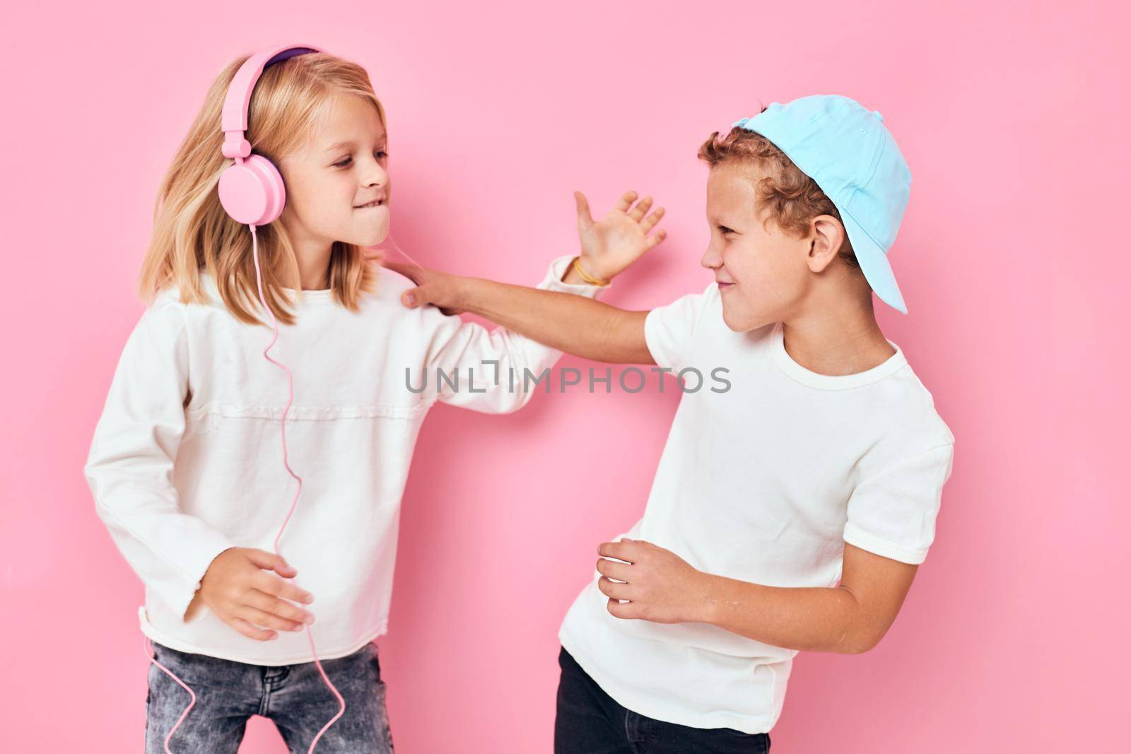 Stylish little boy and cute girl together fun posing pink color background. High quality photo