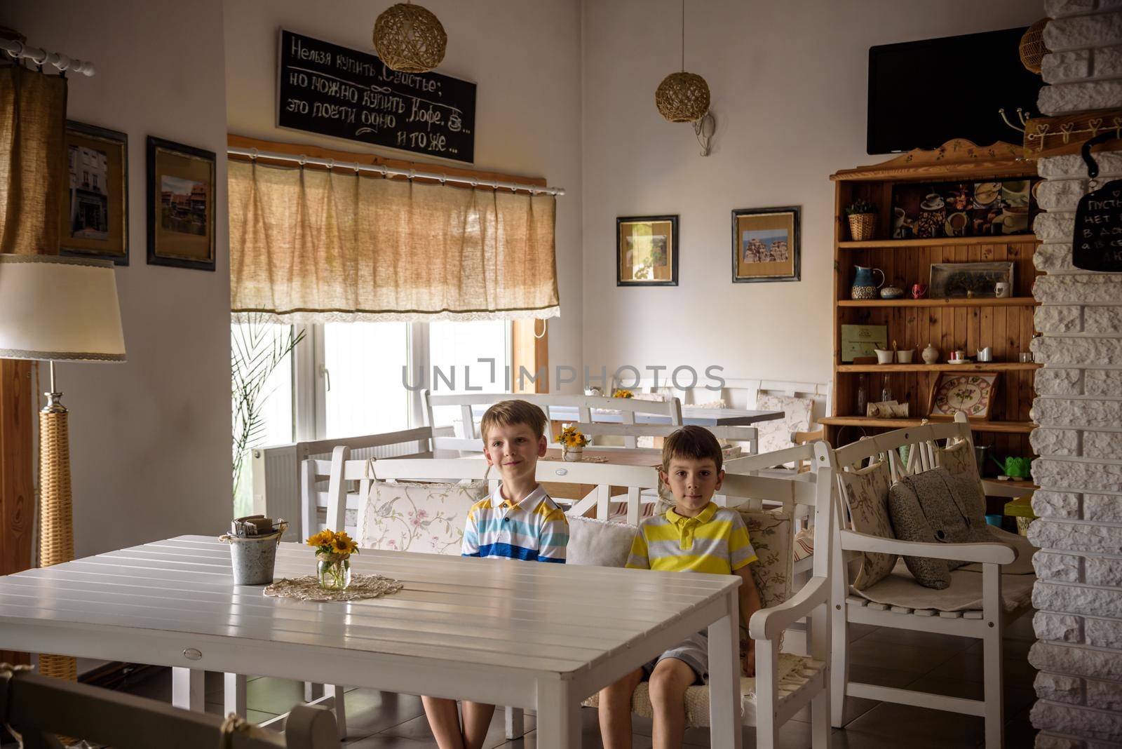Modern cafe interior style, eco environmental with plant on wall, coffee shop. Two children sitting on bench near table waiting for tasty meal.