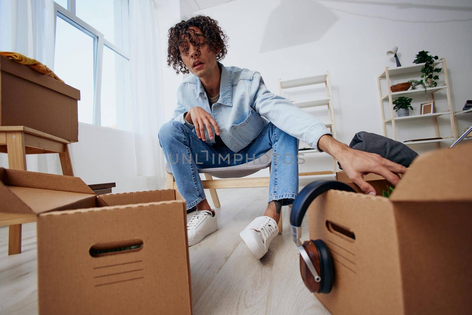 A young man cardboard boxes in the room unpacking headphones Lifestyle. High quality photo
