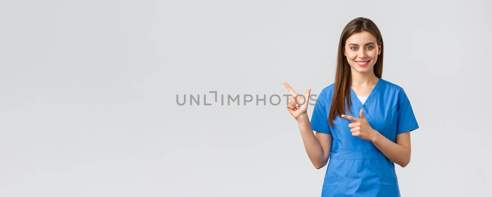 Healthcare workers, prevent virus, insurance and medicine concept. Professional smiling, attractive female nurse or doctor in blue scrubs, physician pointing finger left at banner, recommend clinic.