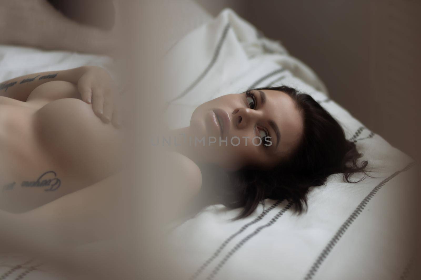 Attractive sensual woman in lingerie on bed in room by 3KStudio