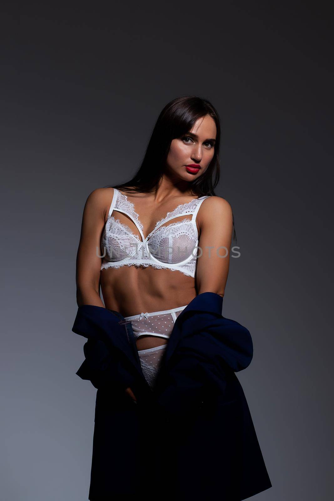 Sensual slim woman in underwear lowering jacket in studio by 3KStudio