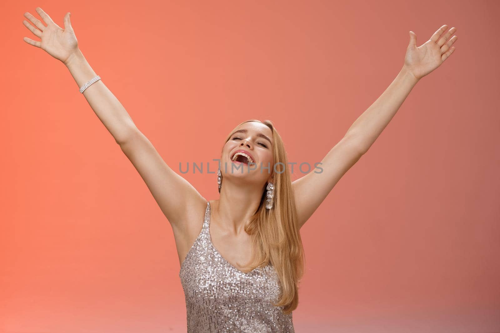 Waist-up carefree happy girl fulfill dream raising hands up sky joyfully close eyes smiling celebrating good perfect news triumphing achieve success victory, standing thrilled red background by Benzoix