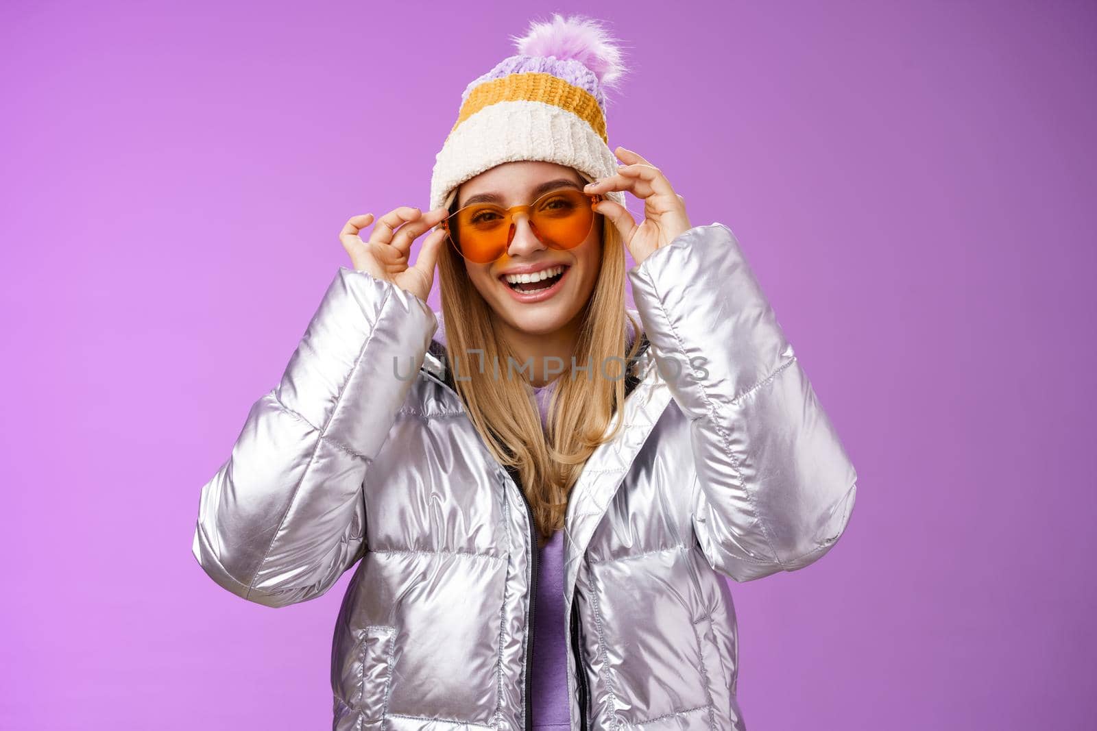 Good-looking charming happy smiling blond girlfriend having fun vacation girlfriends put on sunglasses grinning delighted wear cool silver glittering jacket warm winter hat, purple background.