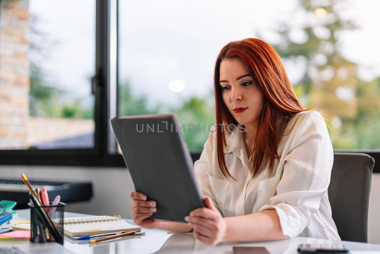 Young woman using tablet at work in home by CatPhotography