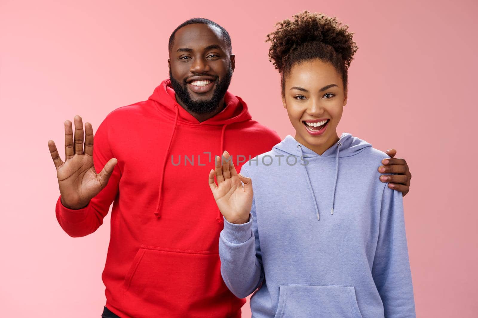 Happy african-american couple man woman hugging friendly guy embracing girl supportive together waving you greeting say hello smiling happily inviting come in welcoming, standing pink background by Benzoix