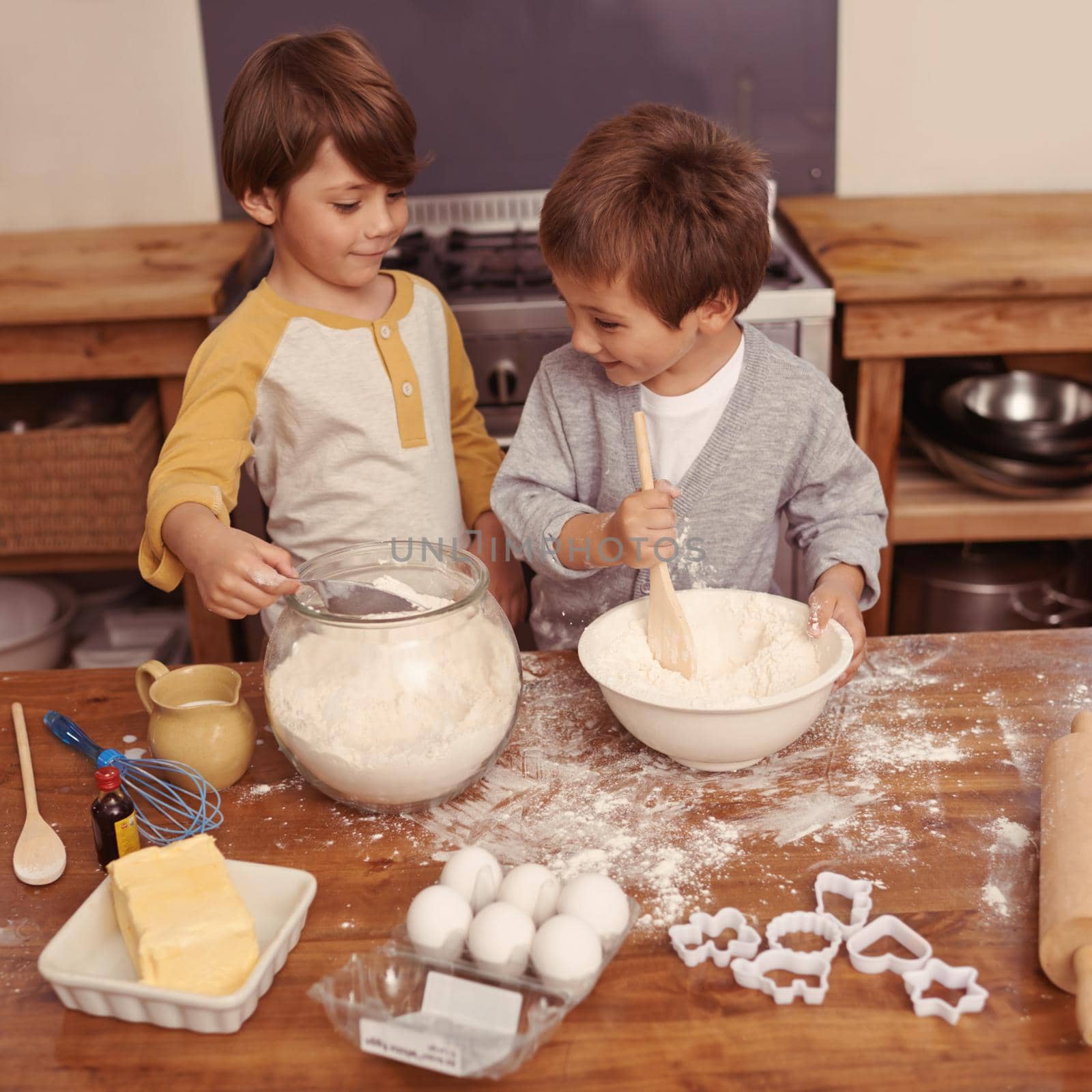 Im mixing this..what are you doing now. Shot of al little boys baking in a kitchen. by YuriArcurs