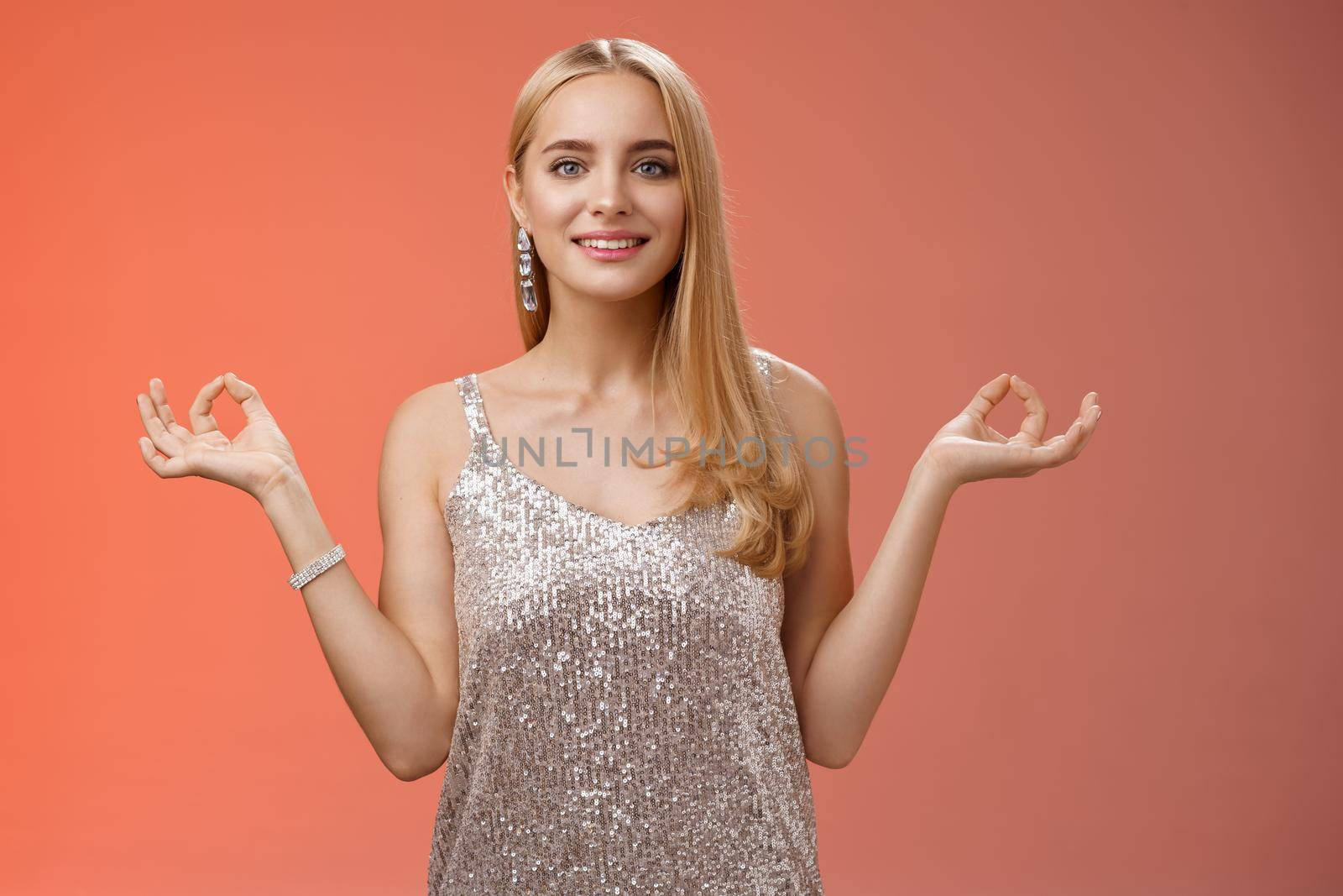 Calm relieved happy fabulous young blond woman in silver stylish luxury dress standing relaxed red background zen lotus pose reach nirvana smiling peaceful carefree meditating breathing practice by Benzoix