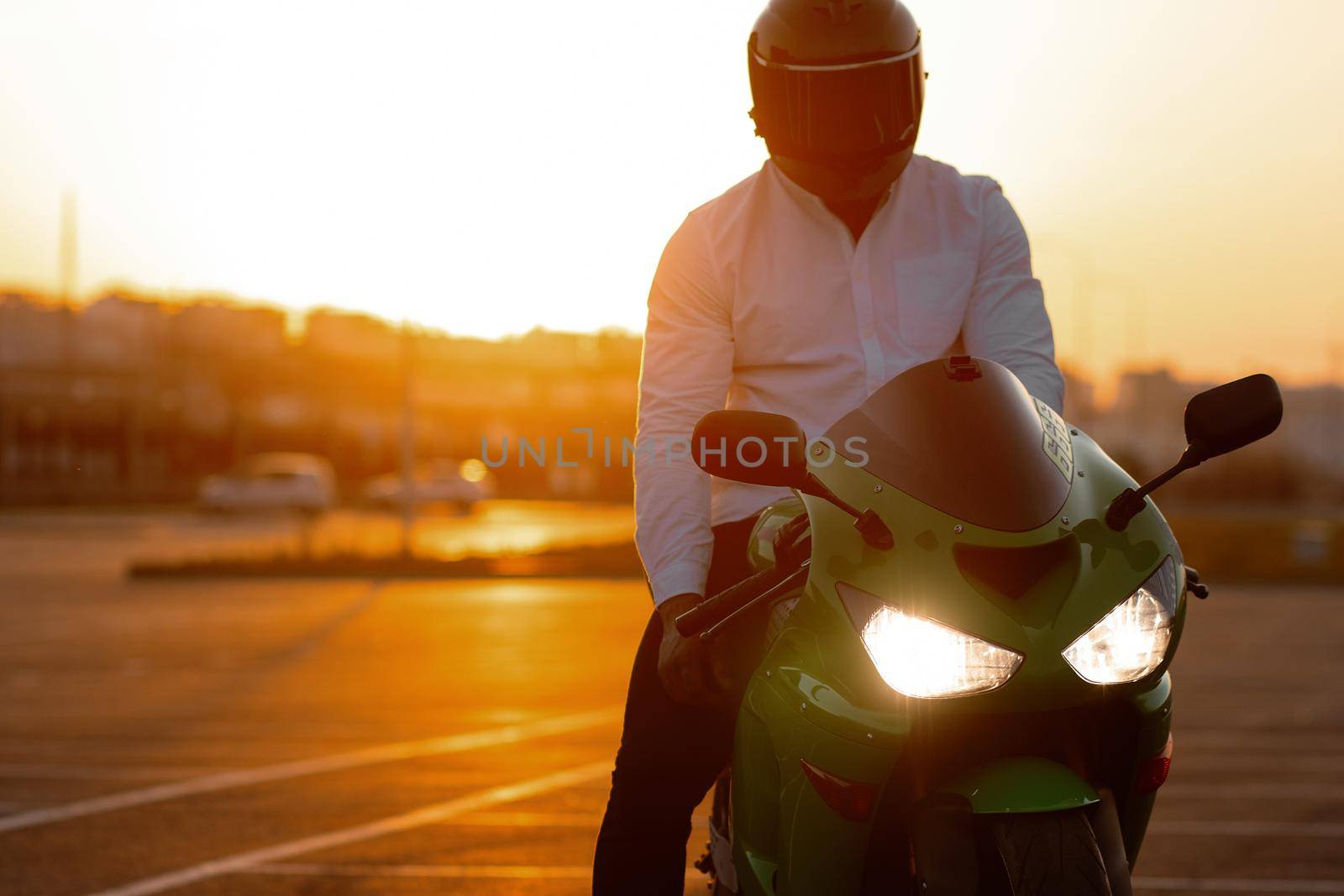 Cool man on motorcycle against sundown sky by 3KStudio