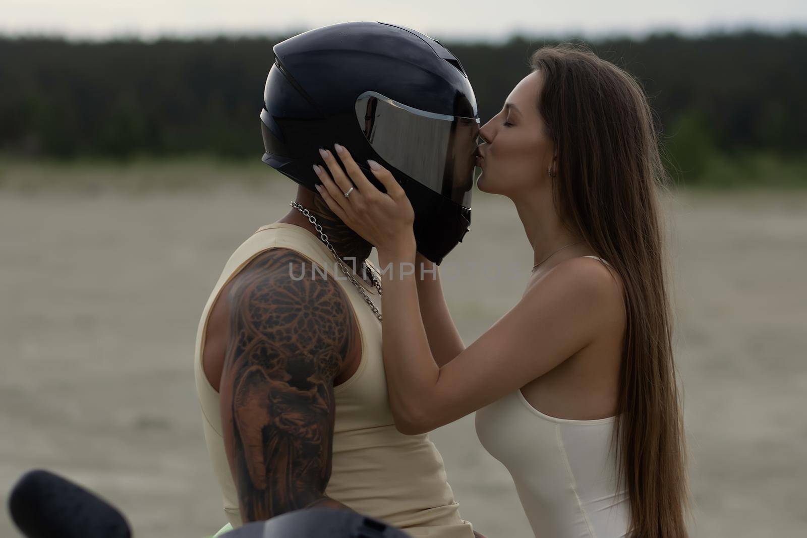 Cool couple embracing near motorcycle in evening by 3KStudio
