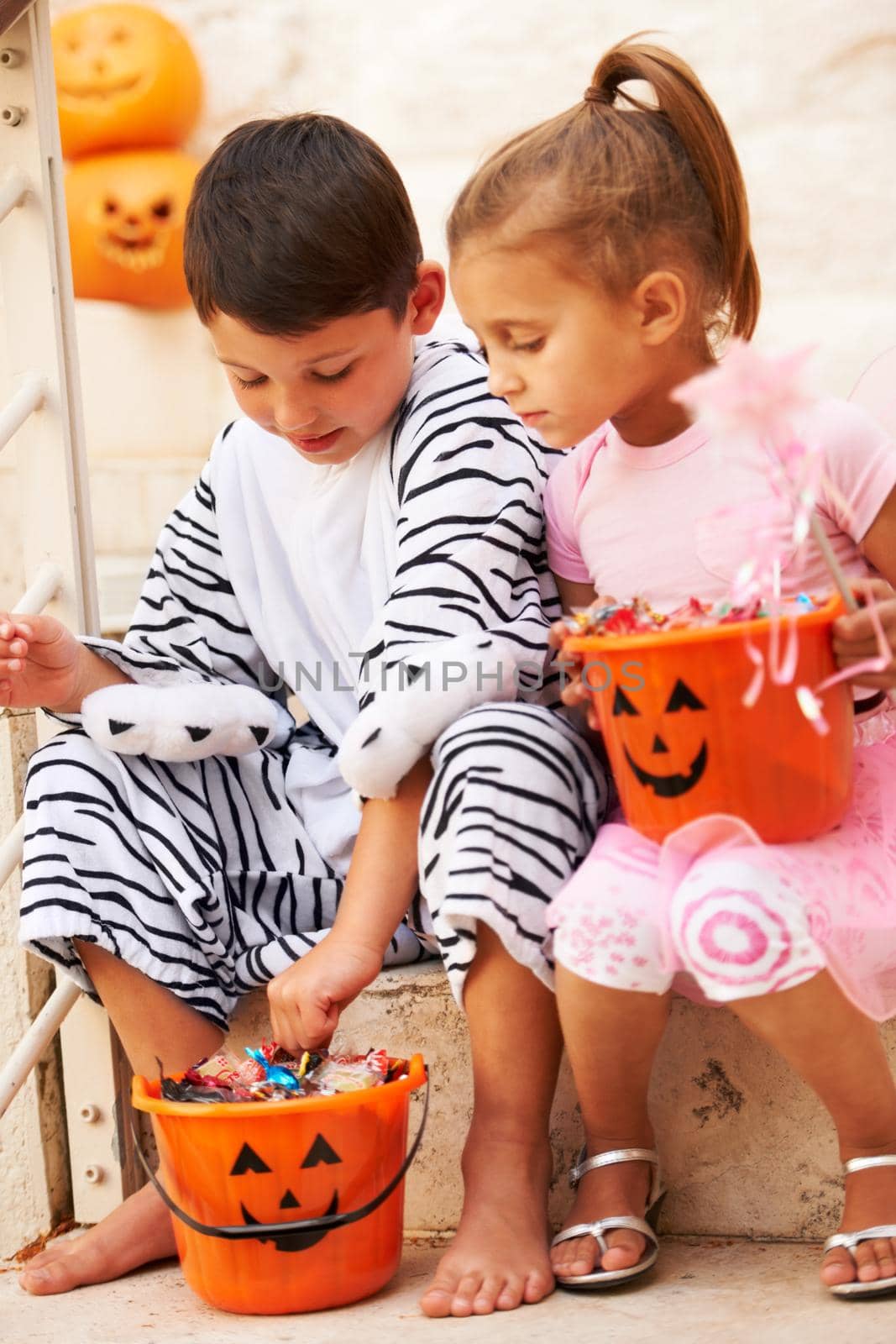 Shot of two cute kids checking out their Halloween candy.