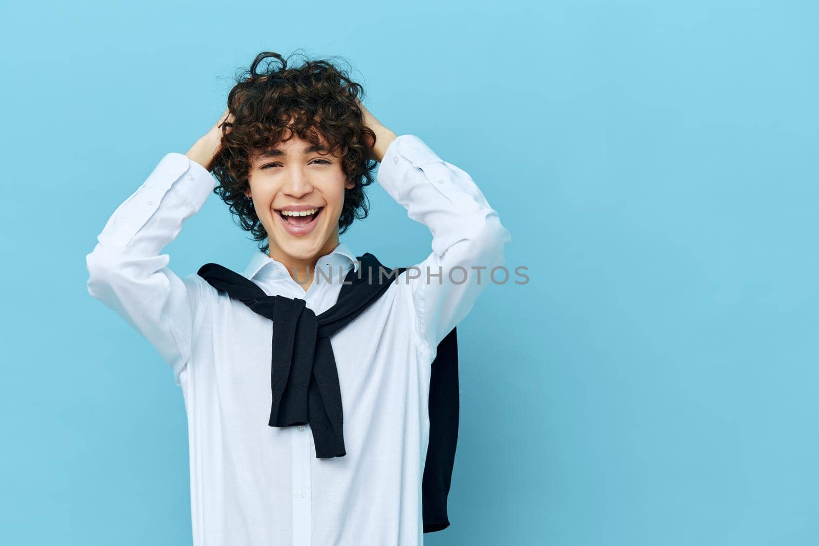 curly guy in a white shirt sweater on the shoulders blue background. High quality photo