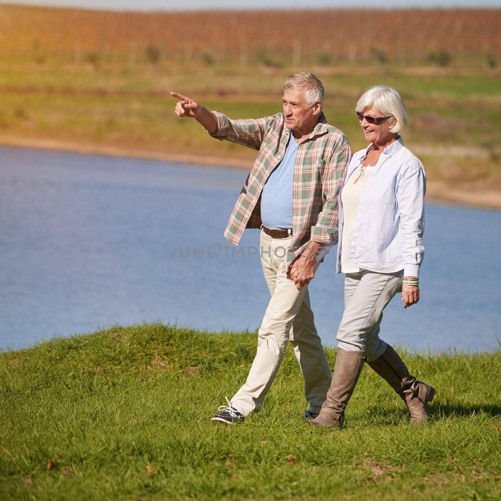 Experiencing all that nature has to offer. Shot of a happy senior couple going for a walk at the lake. by YuriArcurs