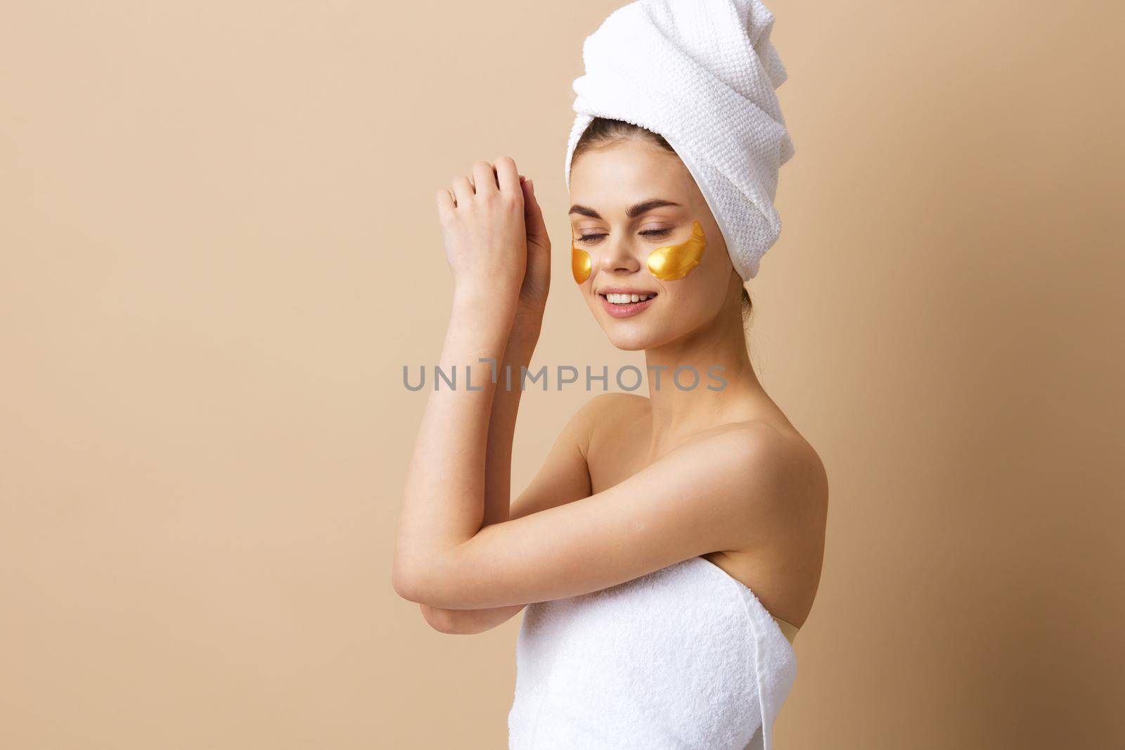 portrait woman with a towel on his head gesturing with his hands skin care beige background. High quality photo