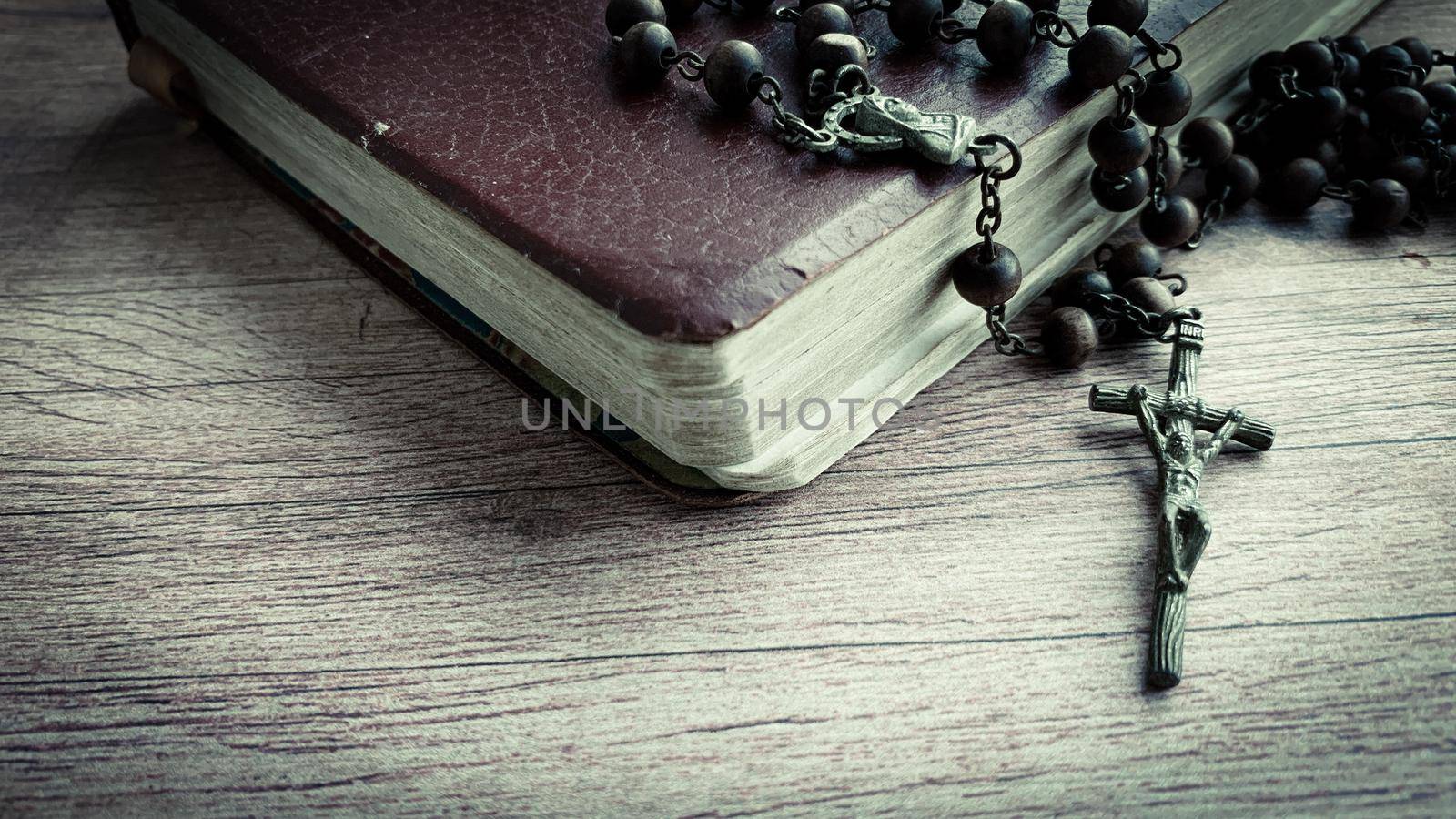 Holy Bible and Holy Rosary on wooden desk. Religious concept