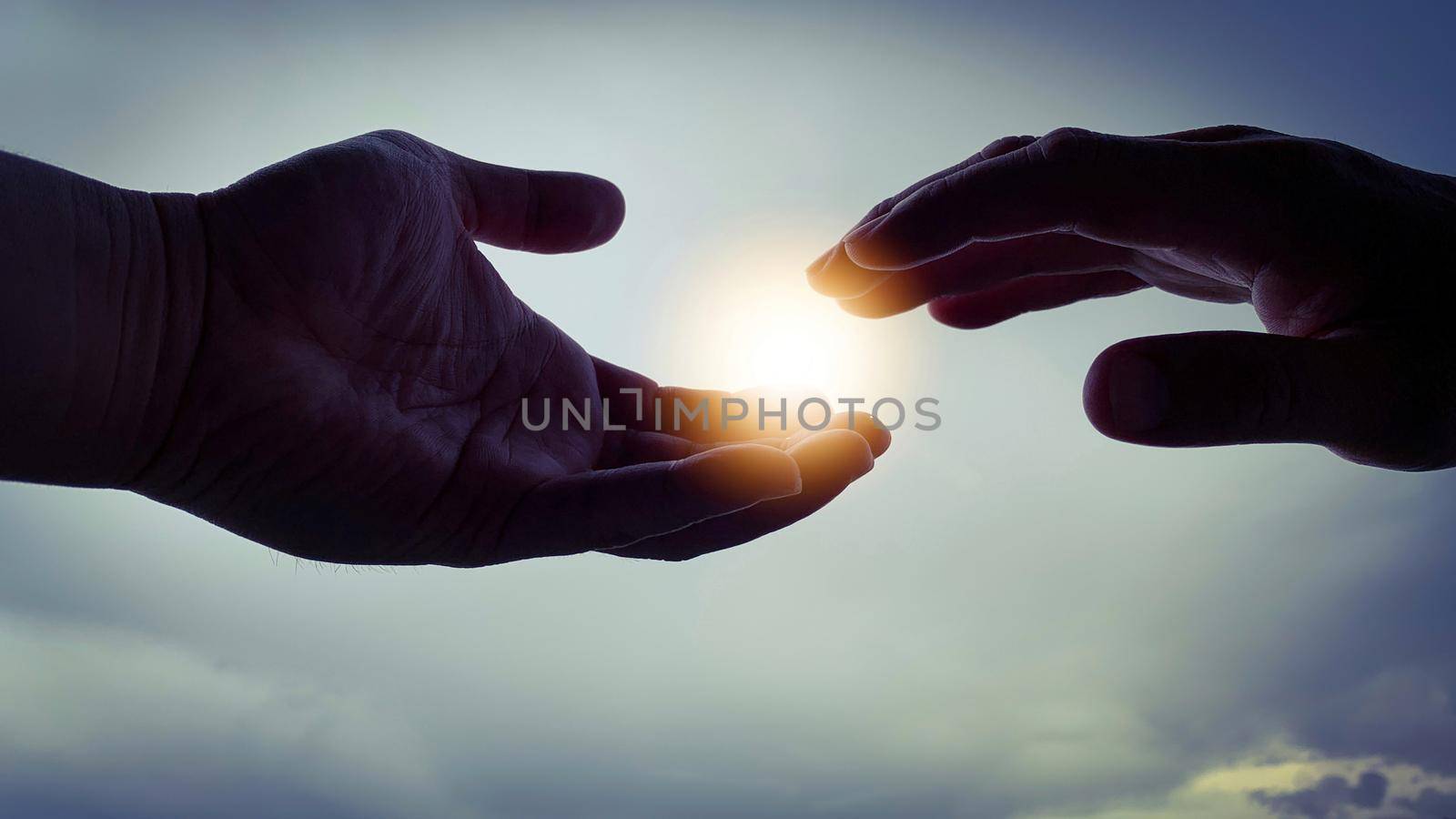 Two hands reaching out to bright shining light. Religious concept