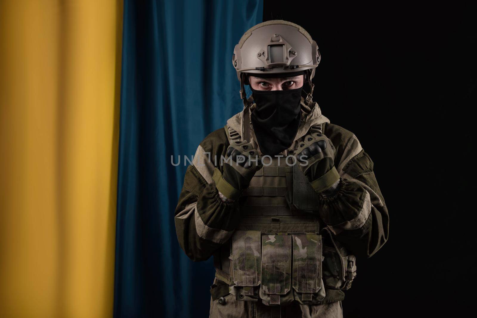 a male soldier in a military uniform and helmet on the background of the national flag of Ukraine by Rotozey