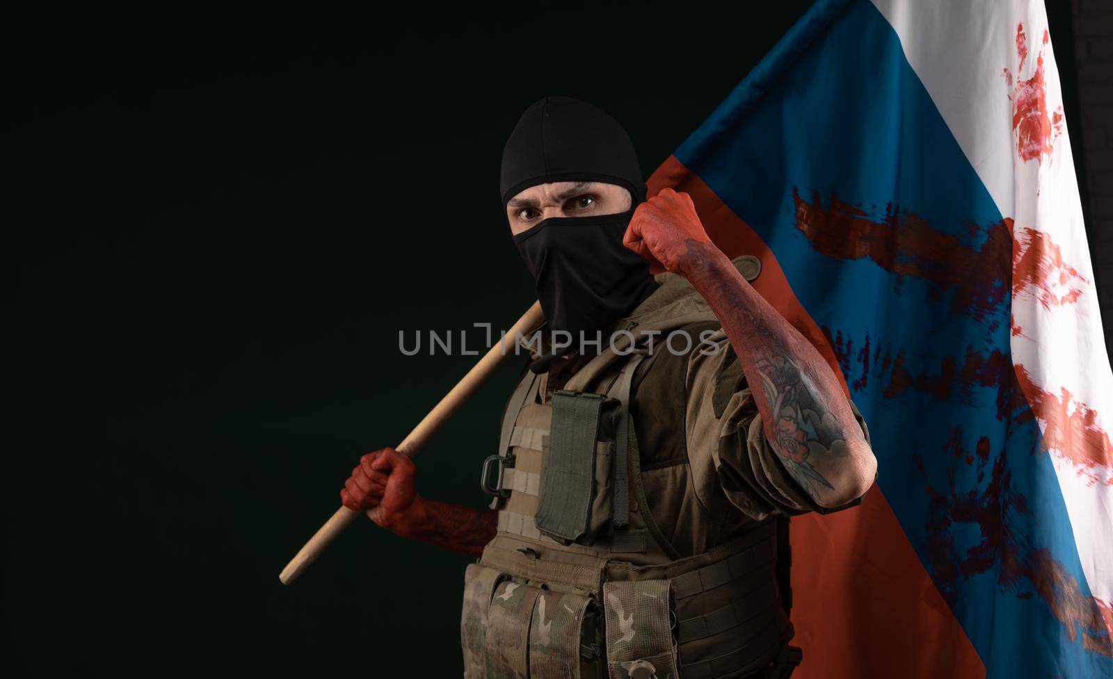 a male soldier in a military uniform with a balaclava and hands covered in blood holds a bloody flag of Russia on a black background by Rotozey