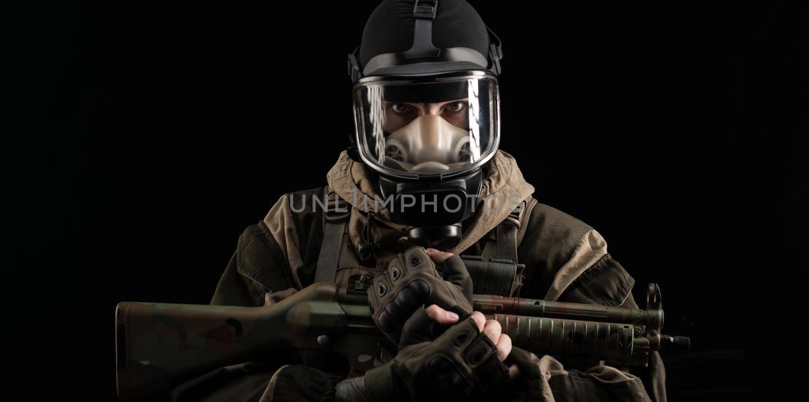 man in a military uniform and a gas mask holds a weapon with an angry expression of emotion