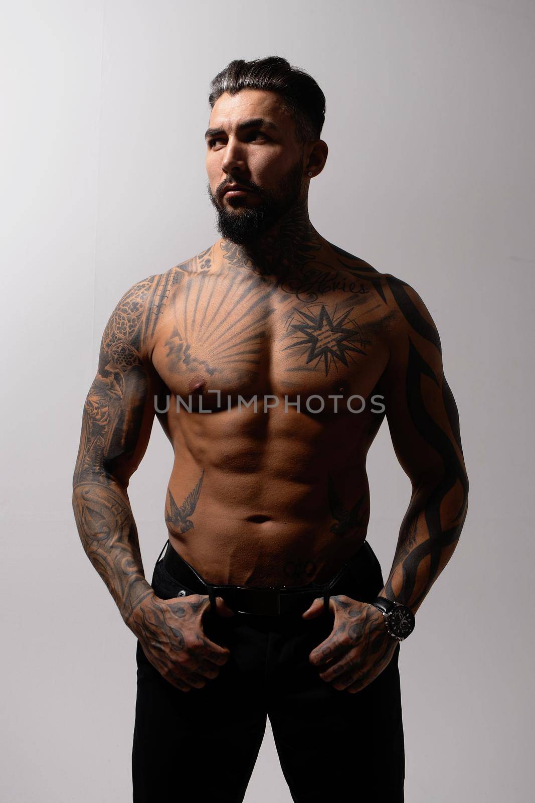 Muscular shirtless tattooed guy in studio by 3KStudio