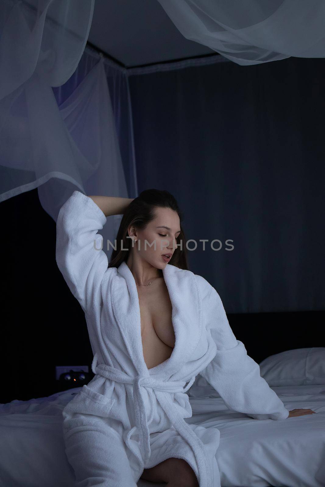 From above of topless sexy female in bathrobe lying on comfortable bed in bedroom