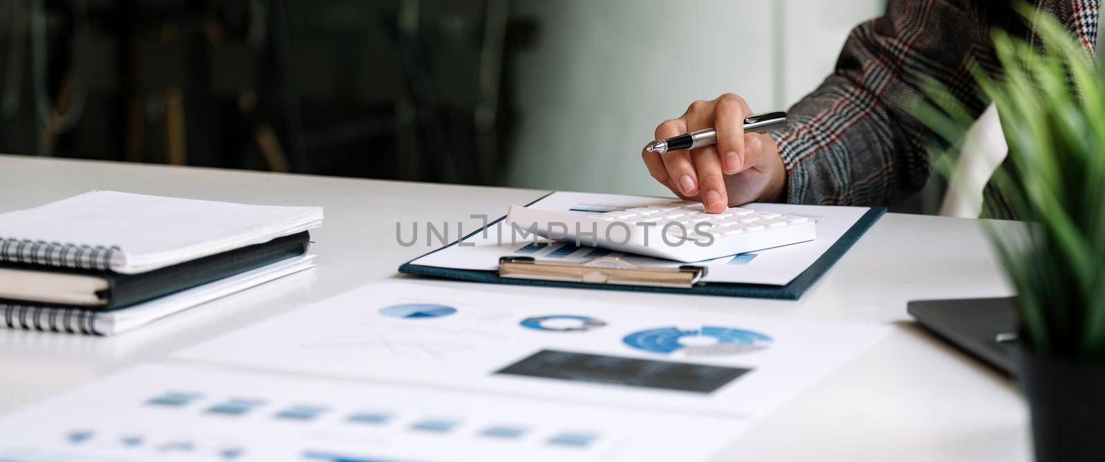 Close up Business woman using calculator for do math finance on wooden desk in office and business working background, tax, accounting, statistics and analytic research concept.