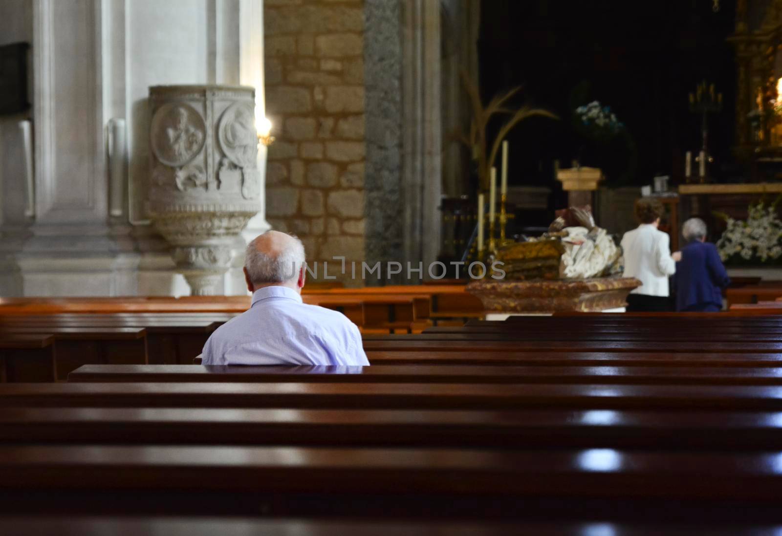 The elderly man prays in a church