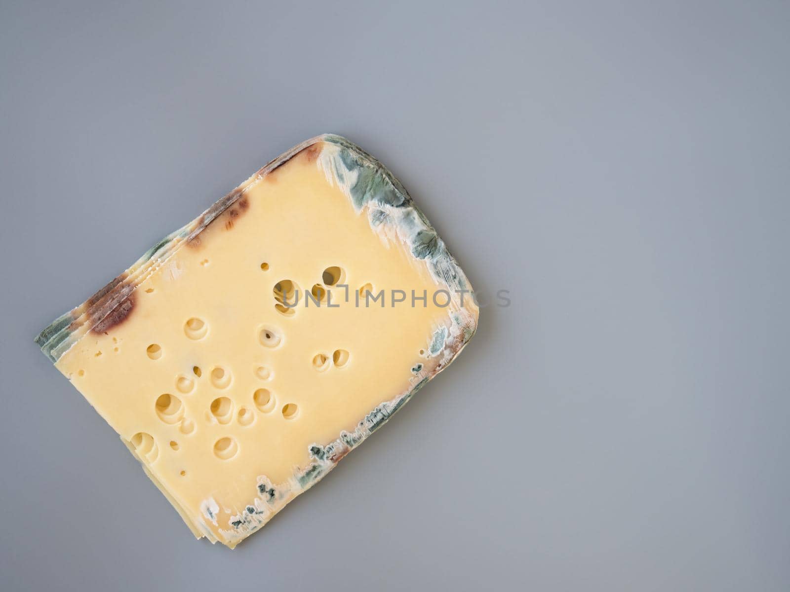 Expired moldy hard cheese purchased at the supermarket. Wastage of Lycopersicon. Incorrect long-term storage. Food waste in supermarkets. Rotten meal on the grey background. Copy space