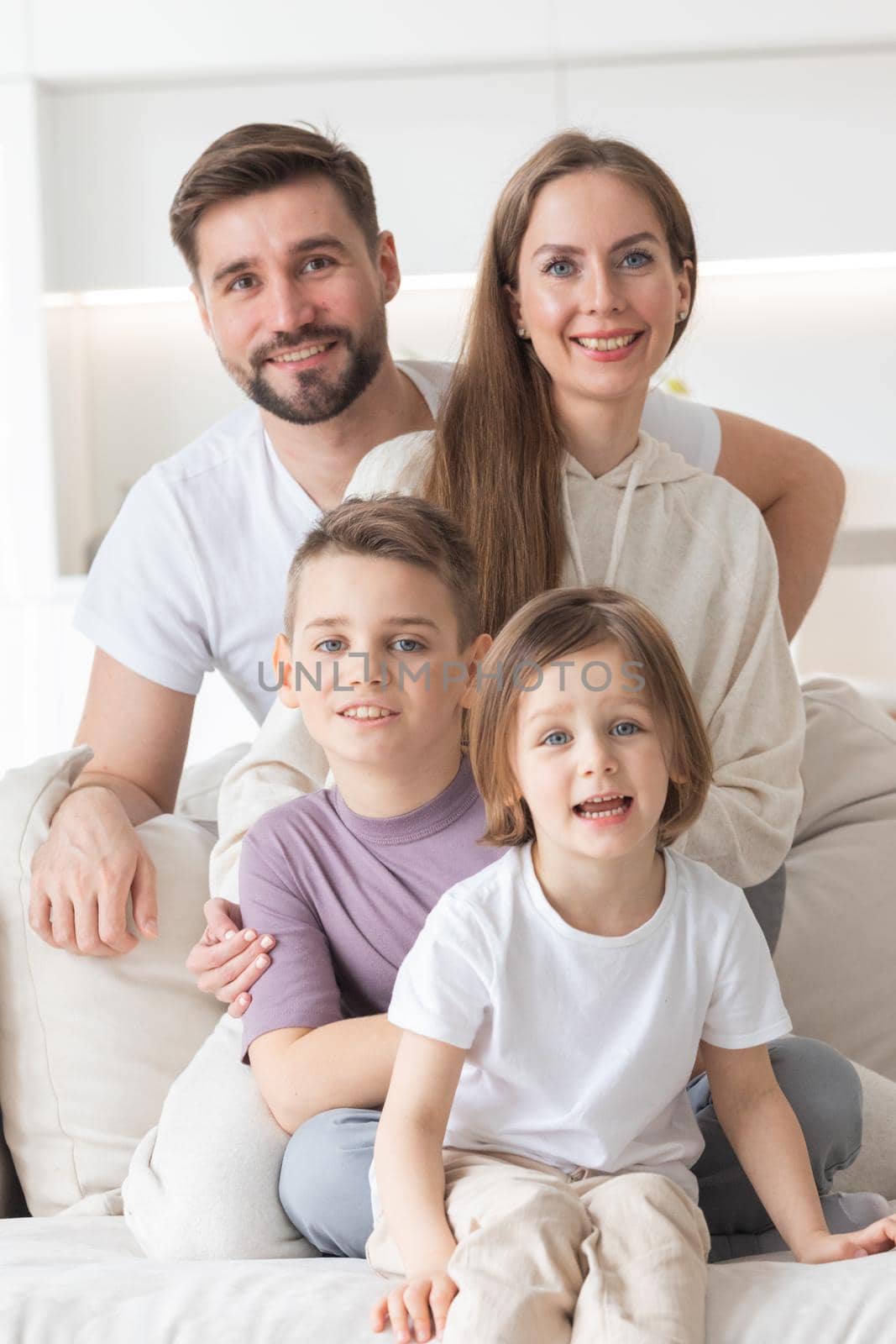 Happy family of parents with children sitting together on sofa at home