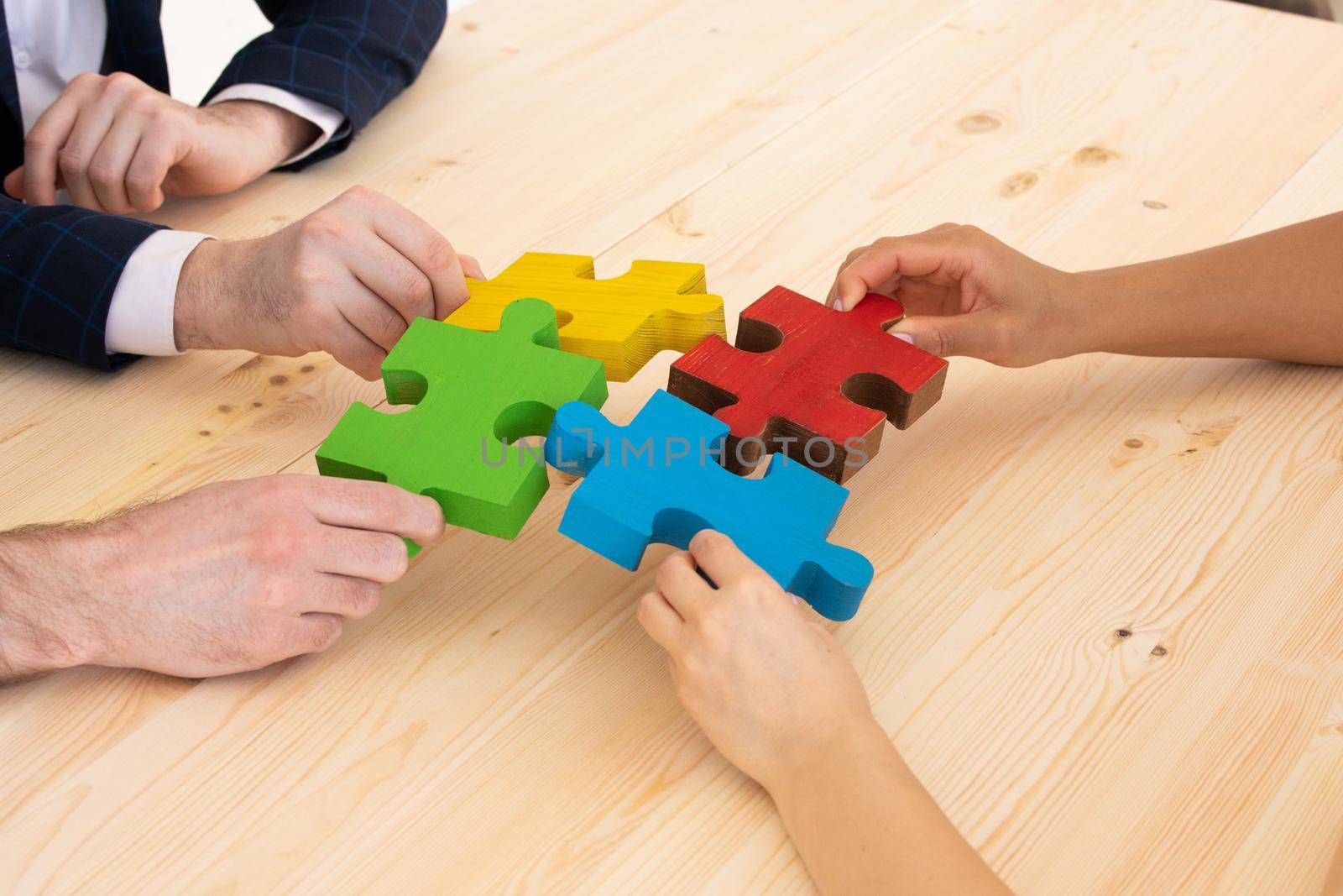 Diverse business people helping in assembling puzzle, cooperation in decision making, team support in solving problems and corporate group teamwork concept, connecting pieces