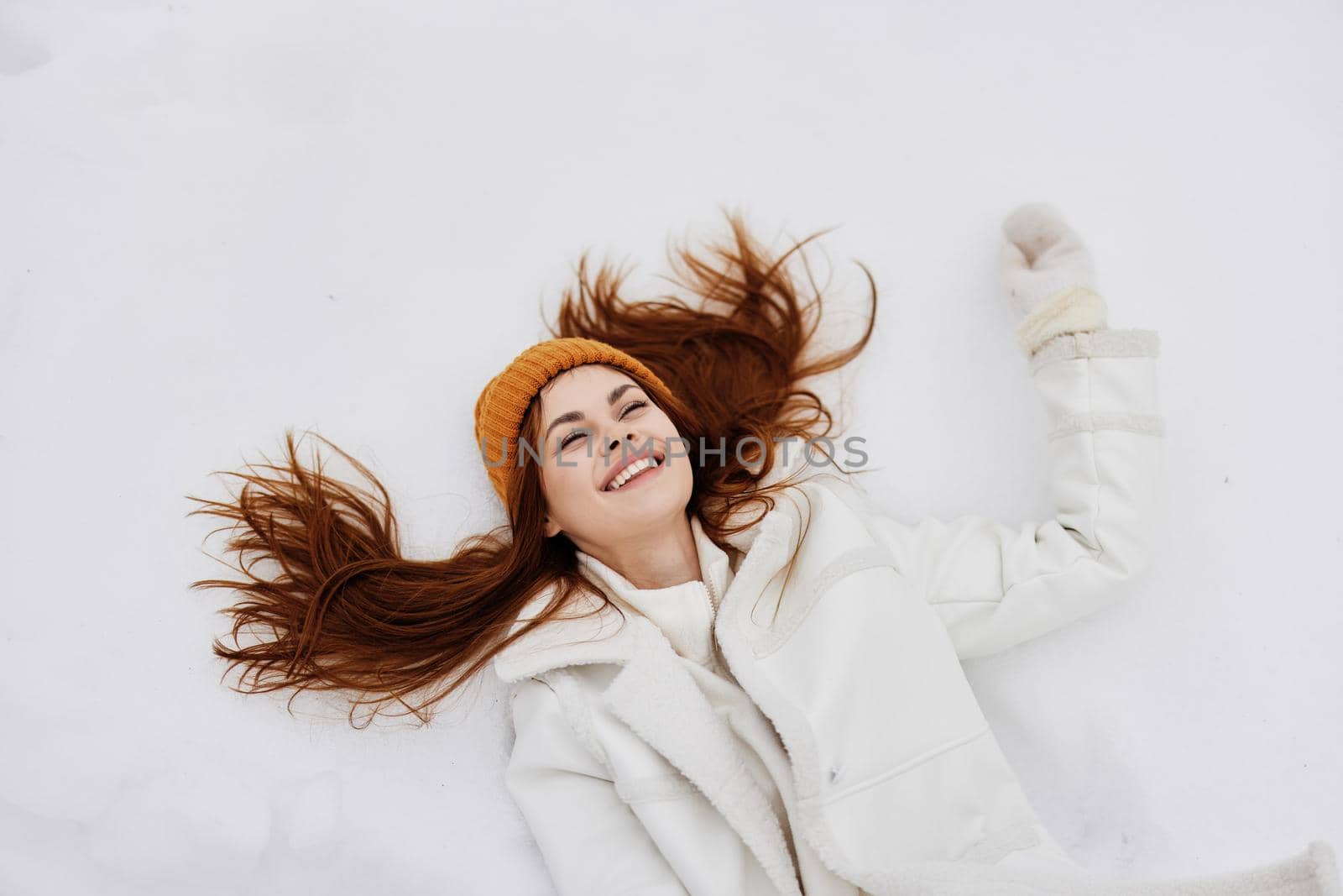 Happy young woman lies on the snow fun rest nature Lifestyle. High quality photo