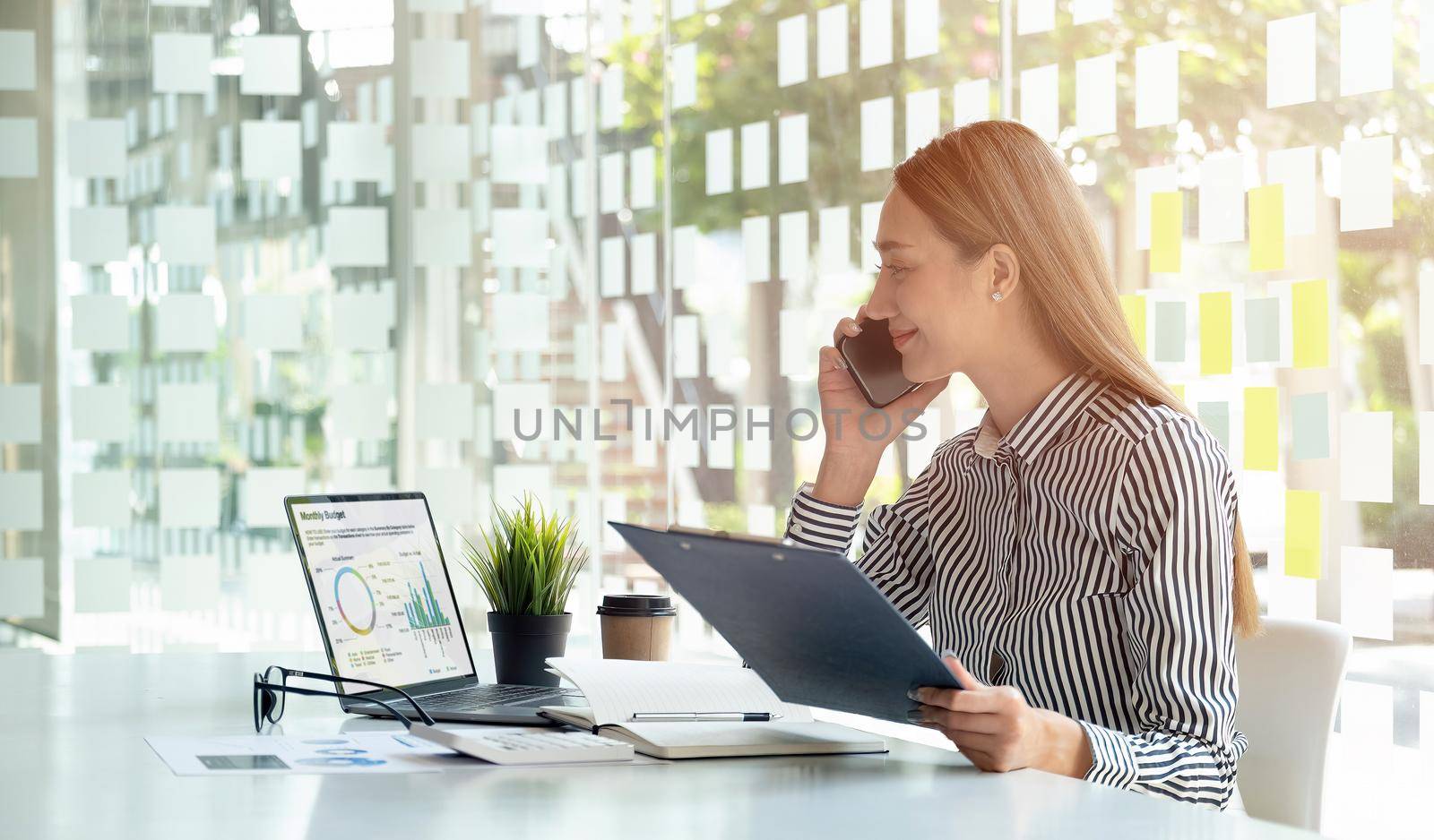 Smiling asian business woman analyst chart financial report and call banker for consult - Financial Concept.