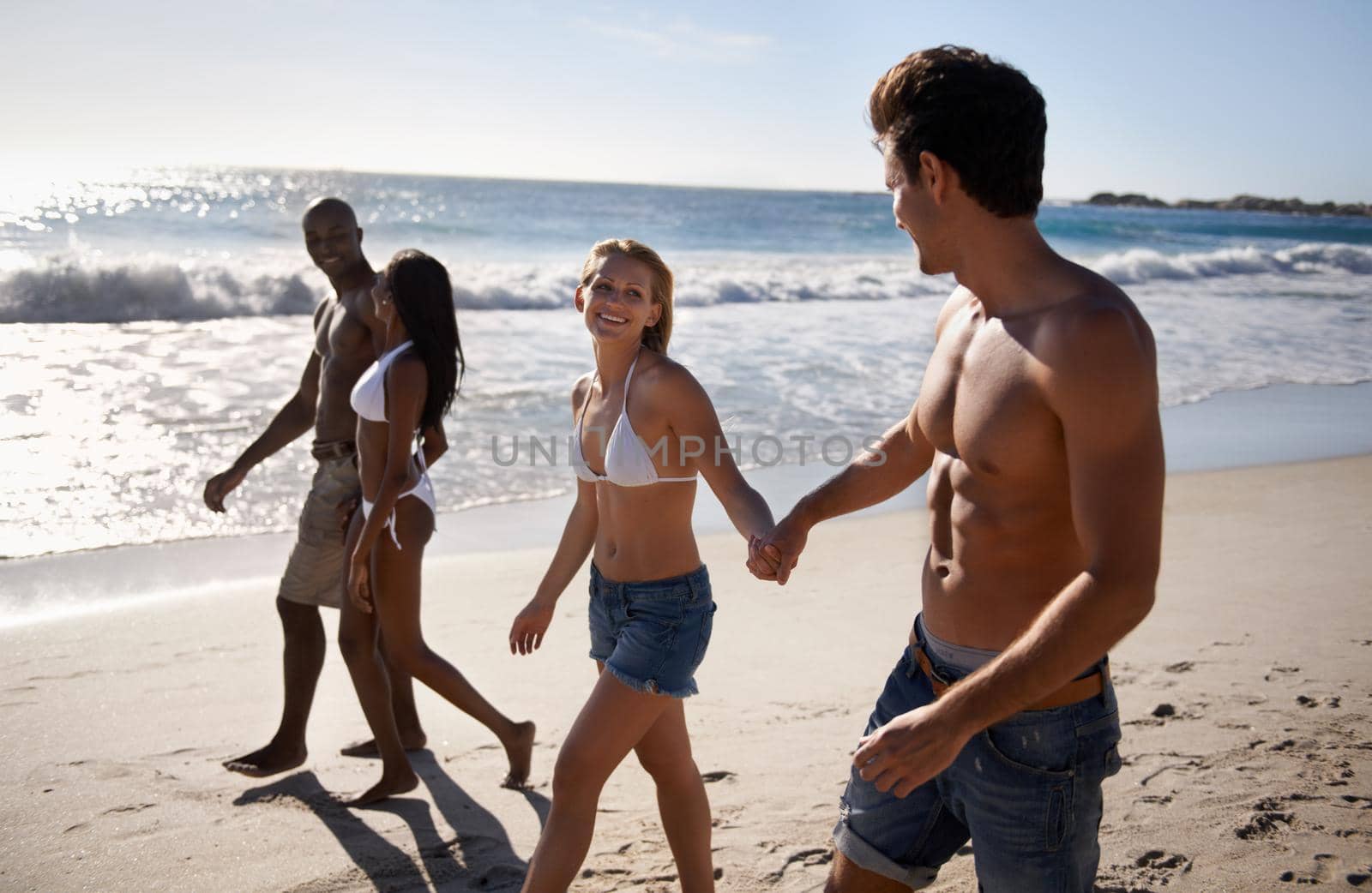 Two young couples taking a walk on the beach together.
