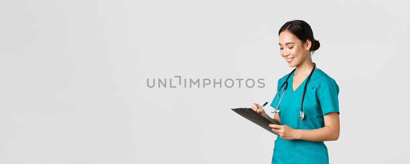 Healthcare workers, preventing virus, quarantine campaign concept. Beautiful smiling asian doctor, nurse running checkup in hospital, looking at clipboard with patient results, examine people by Benzoix