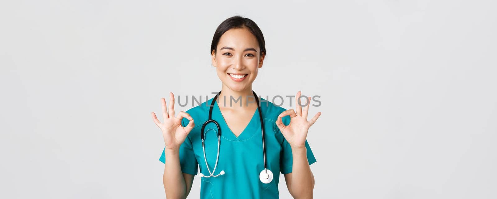 Healthcare workers, preventing virus, quarantine campaign concept. Satisfied good-looking asian female nurse, doctor showing okay gesture in approval, recommend or guarantee perfect service.