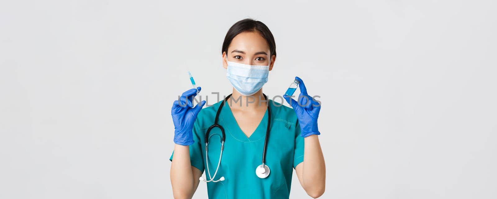 Covid-19, coronavirus disease, healthcare workers concept. Close-up of cute smiling asian female nurse, doctor showing vaccine ampule and syringe, prepare to make injection, white background.