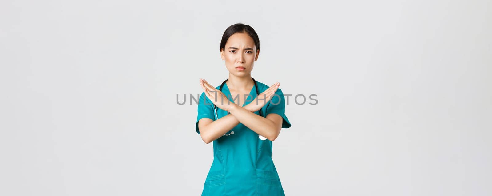 Covid-19, healthcare workers, pandemic concept. Displeased serious-looking concerned asian female doctor show cross gesture, want you stop, prohibit or forbid dangerous action, white background.