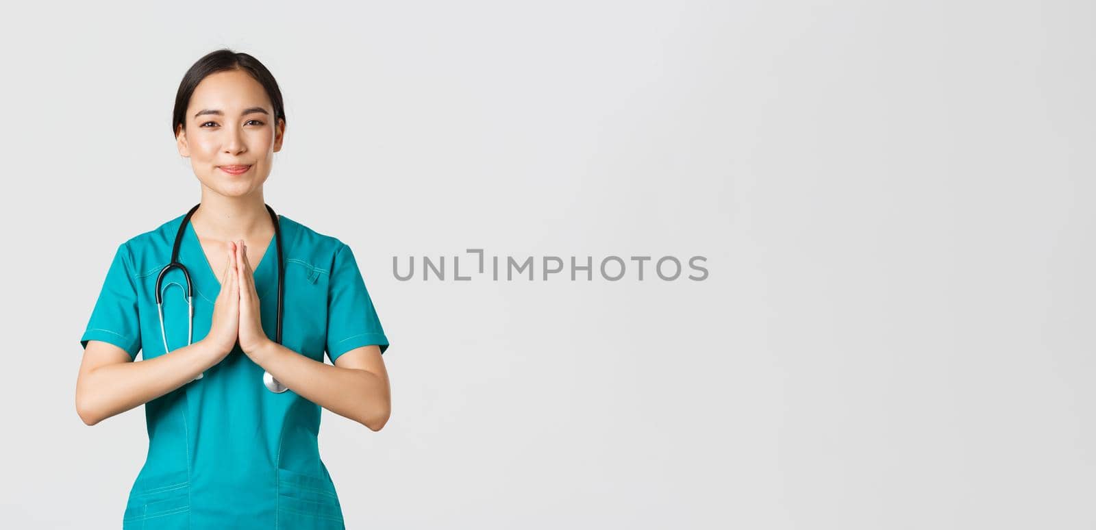 Covid-19, healthcare workers and preventing virus concept. Smiling kind and caring, pretty asian physician, female doctor in scrubs, showing namaste, praying gesture, white background by Benzoix