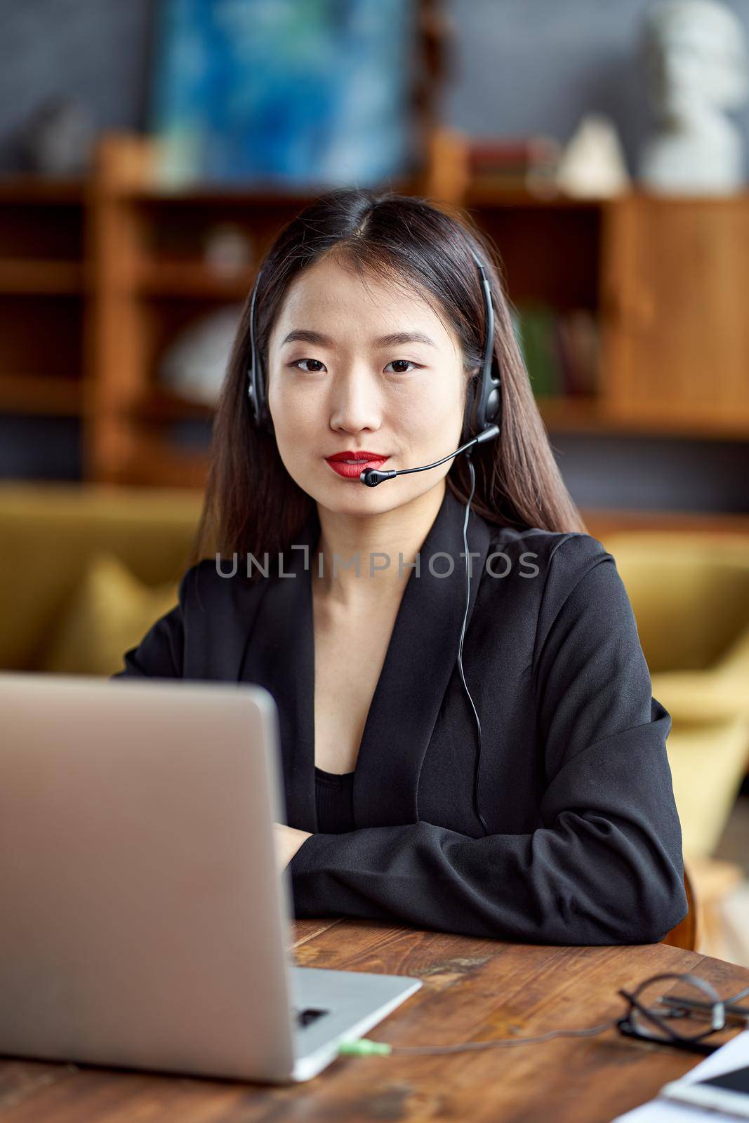 Happy asian businesswoman in headset speaking by conference call and video chat by NataBene