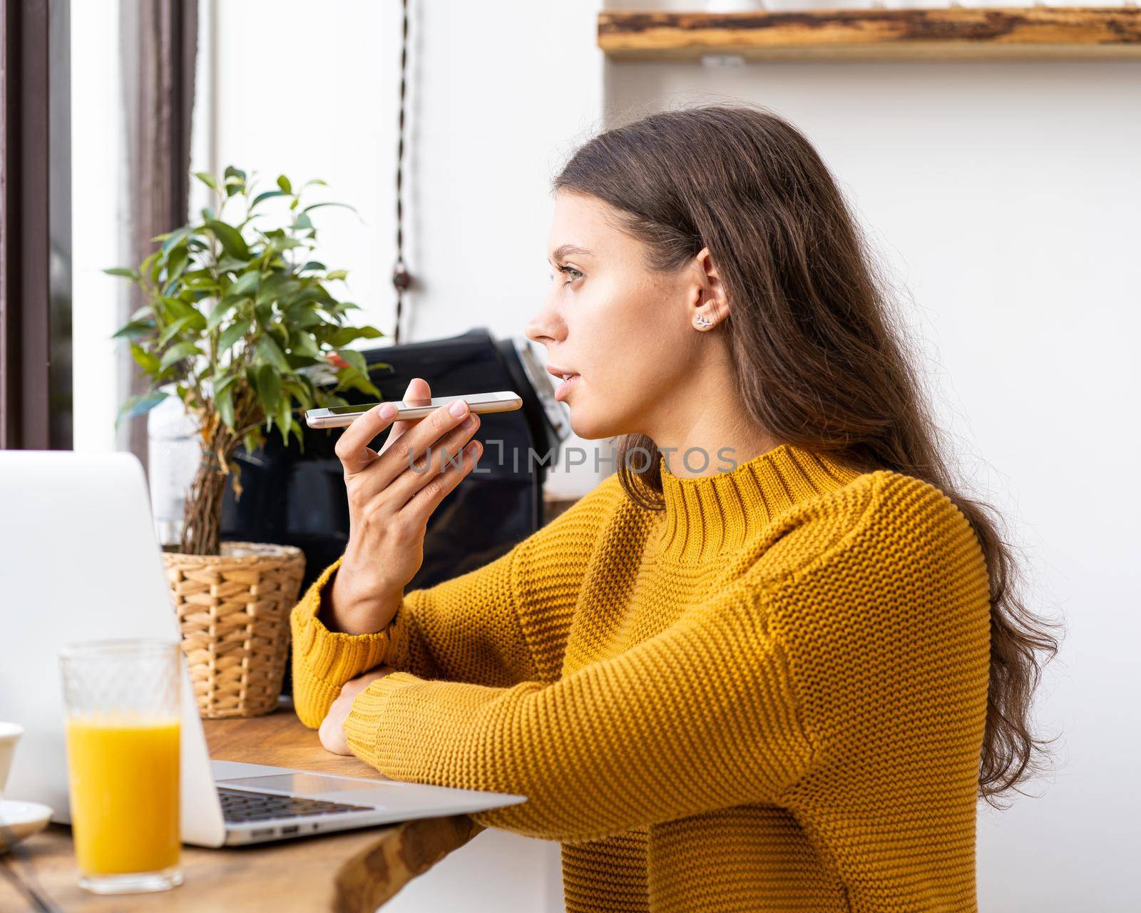 Portrait of positive young woman recording audio message, speaking to microphone by NataBene