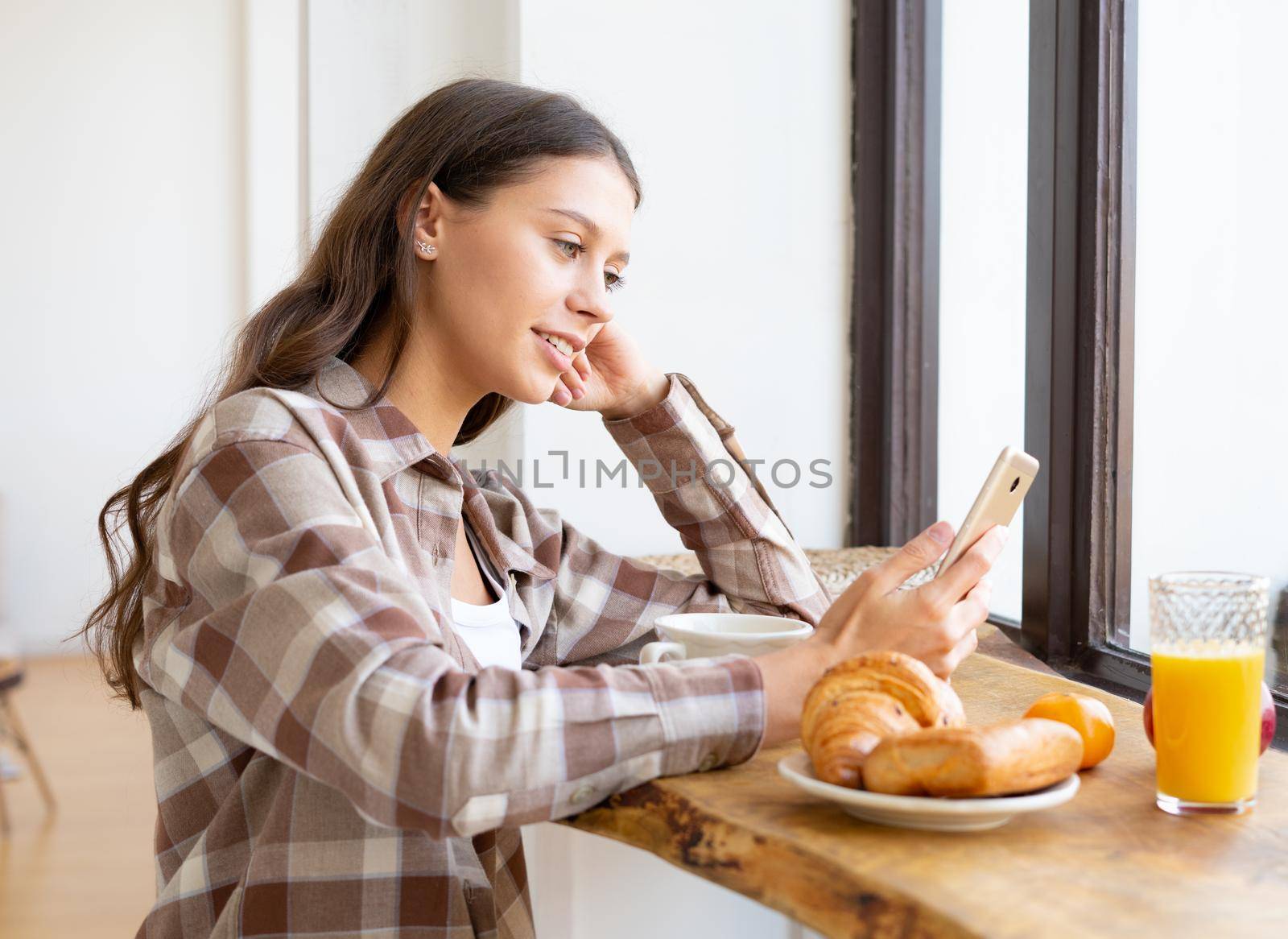 Woman looking for information on Internet, smiling and using mobile, by NataBene