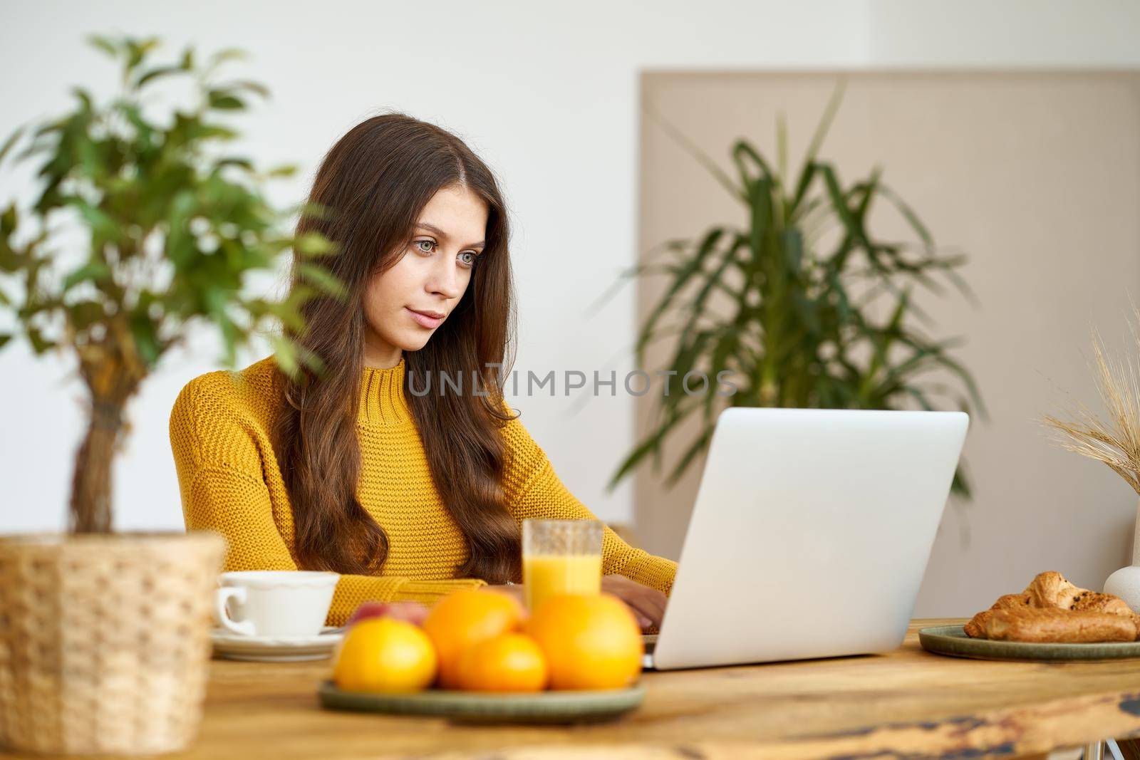 Nice beautiful female with blonde long hair working on laptop sitting at home by NataBene