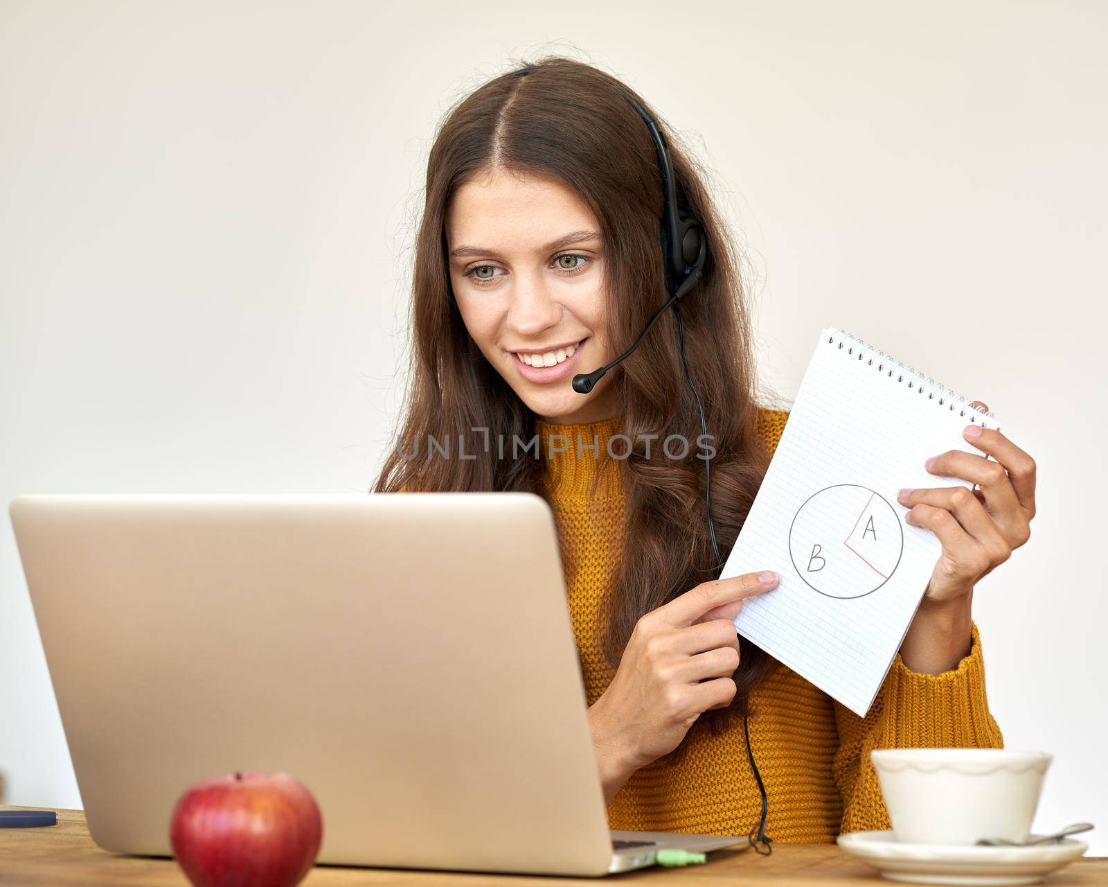 Happy woman in headset speaking by conference call and video chat on laptop in office by NataBene