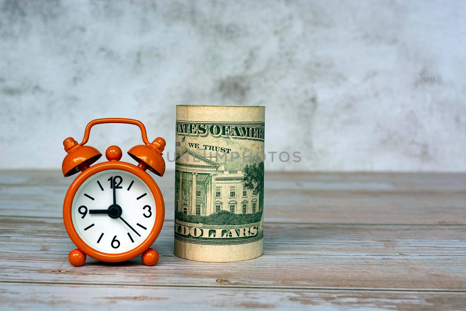 Alarm clock set at 9 o'clock with banknotes on table. Business and tax concept.