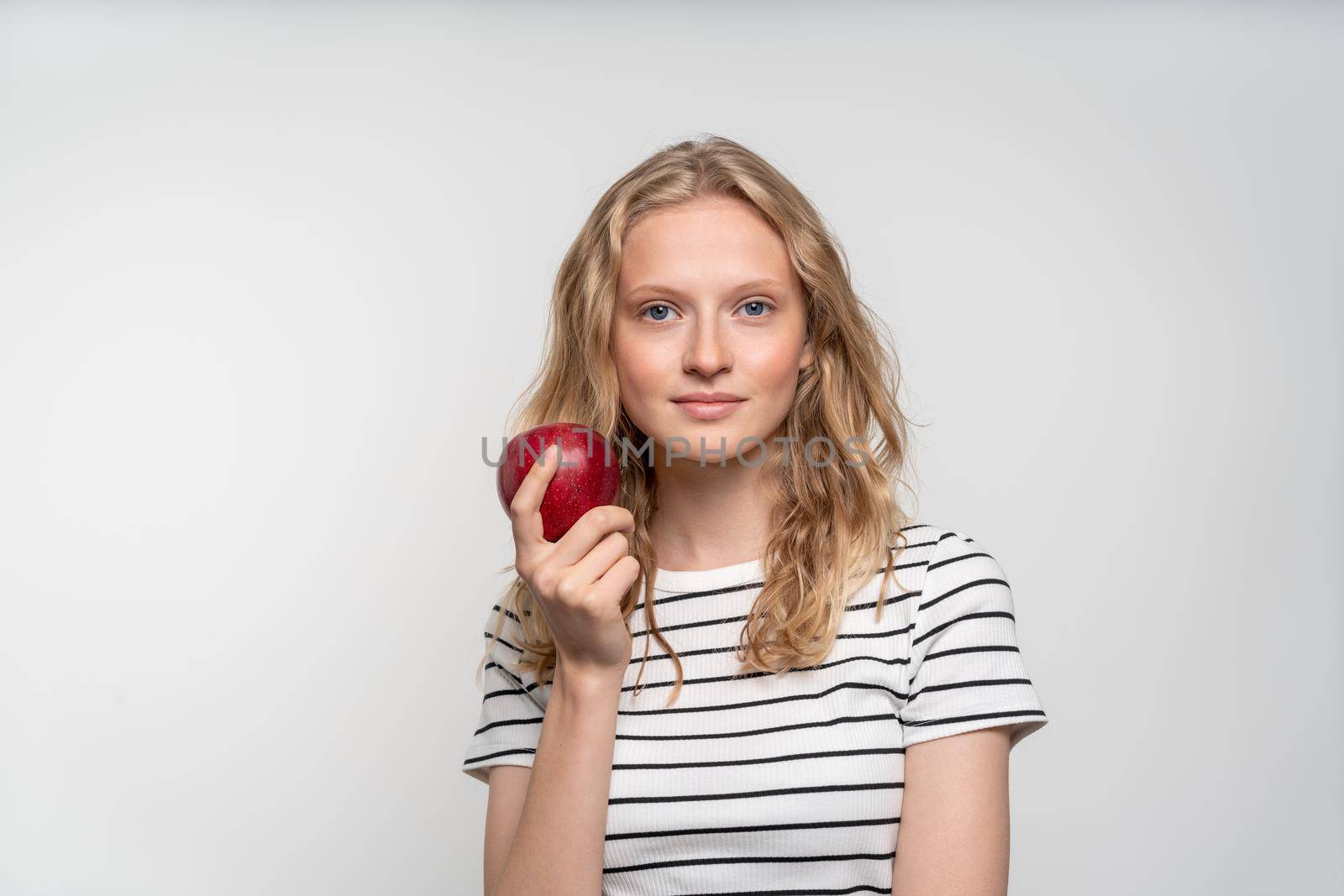 Portrait of young smiling woman with red apple. Fresh face, natural beauty, realistic. Clean young fresh skin without makeup and retouching. Healthy care