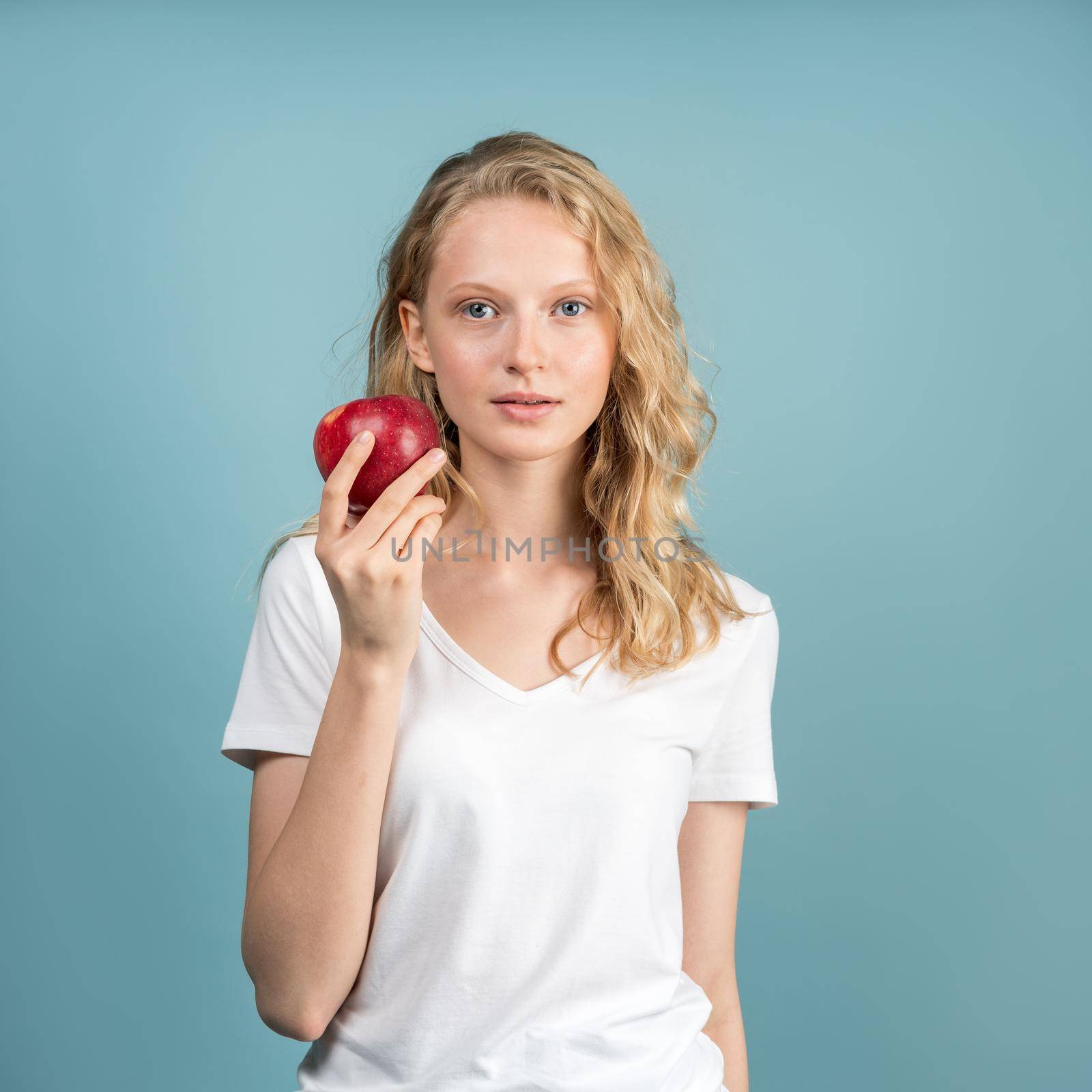 Beautiful young woman with clean young fresh skin without makeup and retouching holding apple. Self-care and care for face. Natural beauty, realistic female