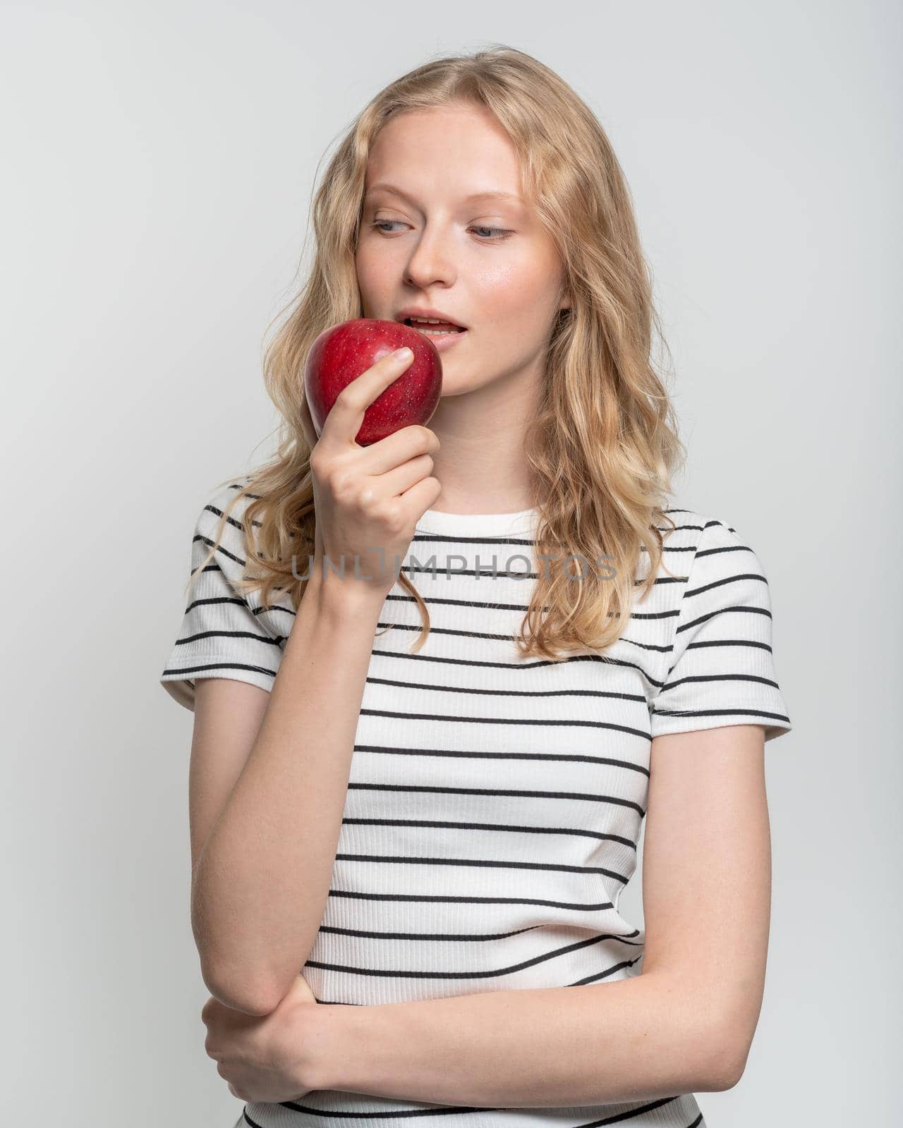 Portrait of young smiling woman bitting red apple. Fresh face, natural beauty, realistic. Clean young fresh skin without makeup and retouching. Healthy care
