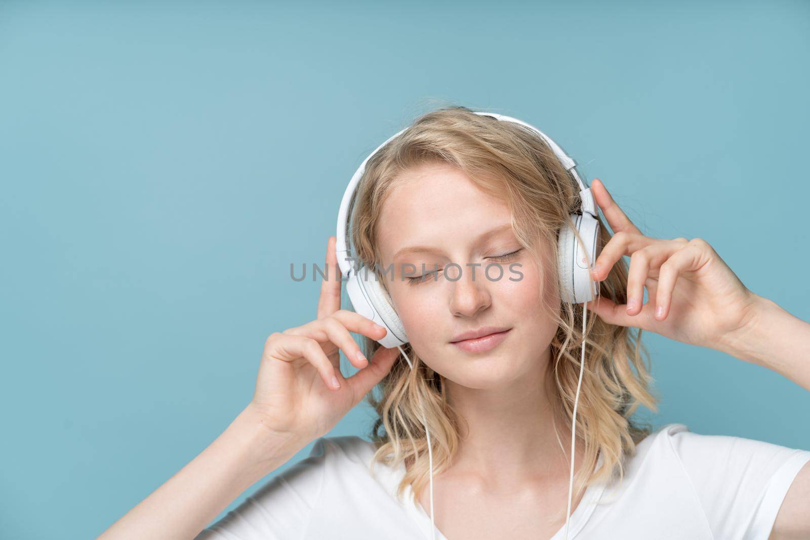 Close up Portrait of young woman closed eyes listening music via headphones by NataBene