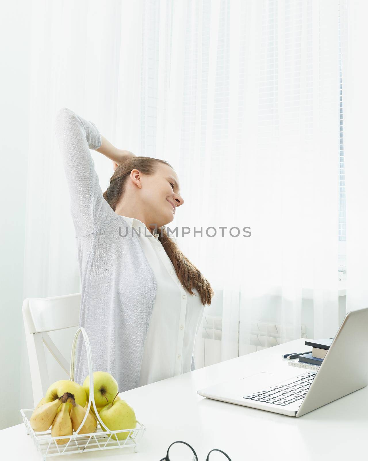 Woman stretches her arms, kneads her back from fatigue. Long sitting at computer, muscle cramps. by NataBene